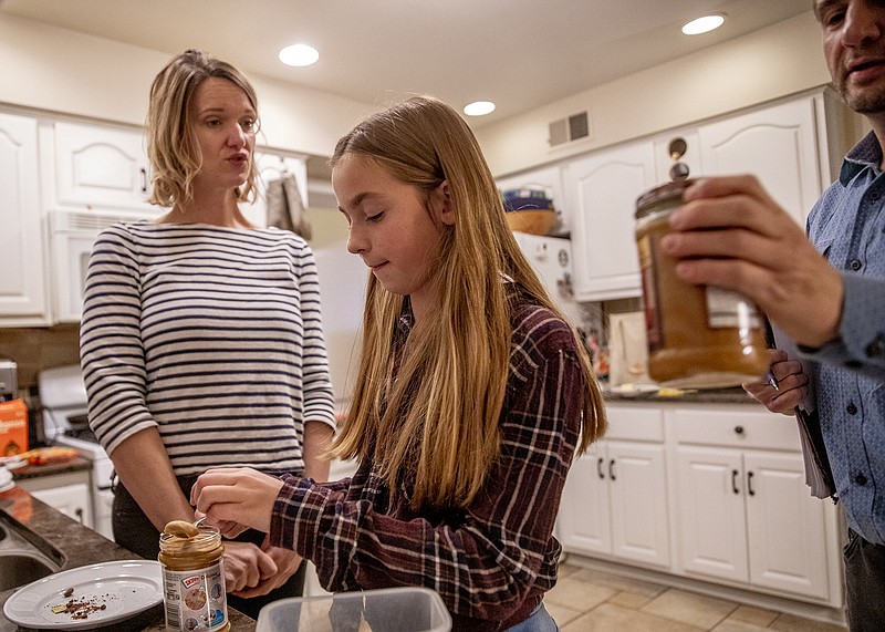 Kate Schonwald, 12, center, and her dad journalist Josh Schonwald try peanut butter during Kate's second session with occupational therapist Karen Dilfer, left, who specializes in food, in the Schonwald's Evanston, Ill. home on Monday, Dec. 2, 2019. (Camille Fine/Chicago Tribune/TNS)