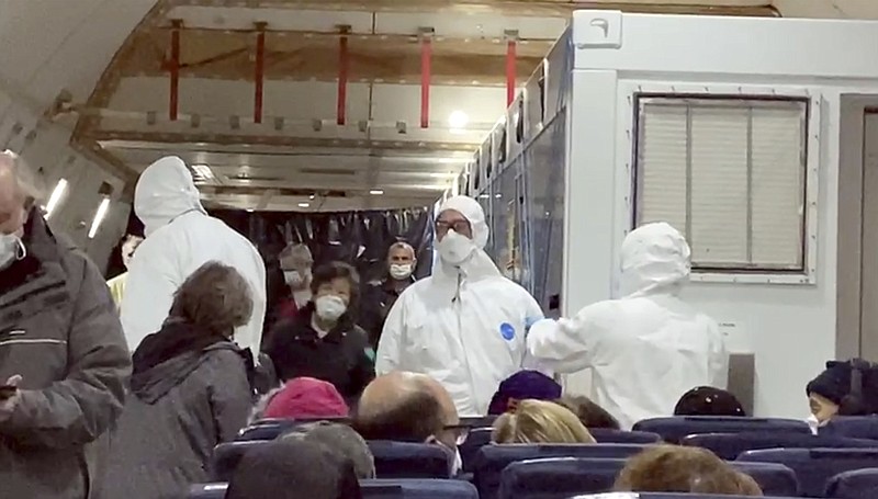 In this image from a video taken on Monday, Feb. 17, 2020, U.S. passengers who evacuated off the quarantined cruise ship the Diamond Princess and officials wait for the takeoff of a Kalitta Air airplane bound for the U.S., at Haneda airport in Tokyo.(Cheryl and Paul Molesky via AP)