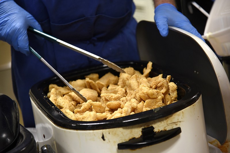 <p>Jenna Kieser/News Tribune</p><p>A volunteer opens a crockpot full of swai fish for the fish fry put on by the Knight of Columbus in March 2019 in Jefferson City.</p>