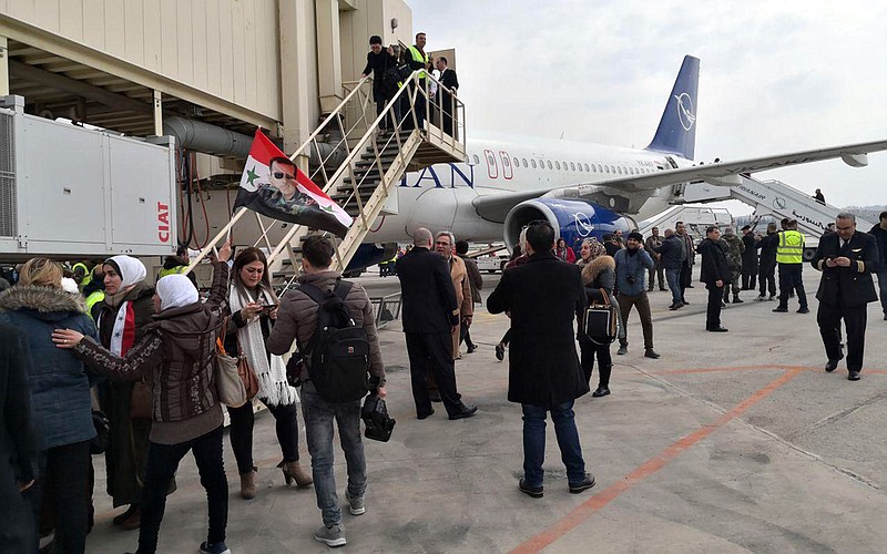 In this photo released by the Syrian official news agency SANA, Syrian officials and journalists disembark a Syrian commercial plane after it landed at Aleppo Airport, Syria, Wednesday, Feb. 19, 2020. The Syrian commercial flight on Wednesday from Damascus, marked the resumption of internal flights between Syria's two largest cities for the first time since 2012. (SANA via AP)