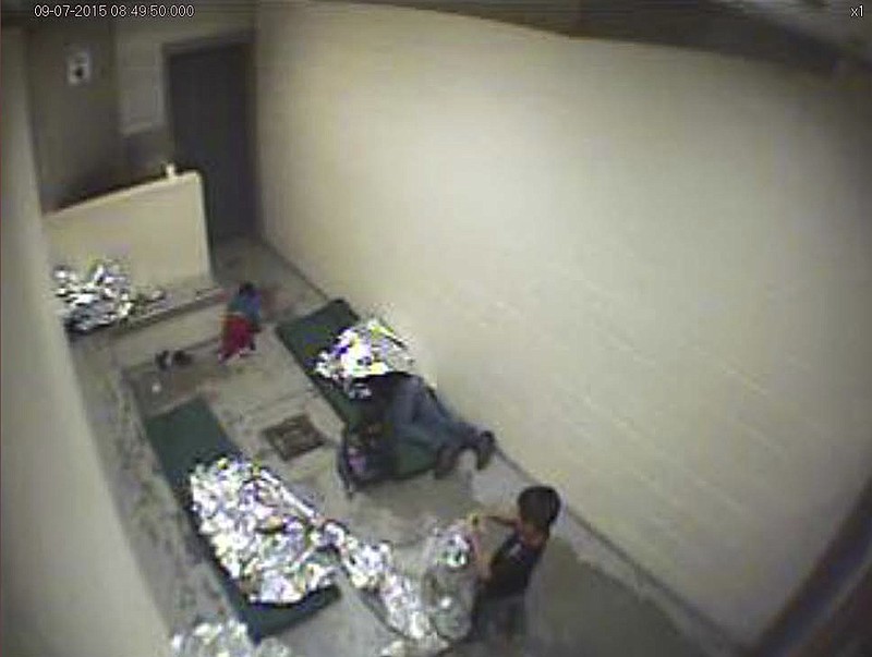 FILE - This September, 2015, file image made from U.S. Border Patrol surveillance video shows a child crawling on the concrete floor near the bathroom area of a holding cell, and a woman and children wrapped in Mylar sheets at a U.S. Customs and Border Protection station in Douglas, Ariz. A U.S. judge in Arizona has issued a permanent order requiring the Border Patrol to provide clean mats and thin blankets to migrants within 12 hours of arriving at a facility. The order issued on Wednesday, Feb. 19, 2020, applies to eight Border Patrol stations in Arizona following a lawsuit that claims the agency holds migrants in overcrowded, unsafe and inhumane conditions. (U.S. Border Patrol via AP, File)