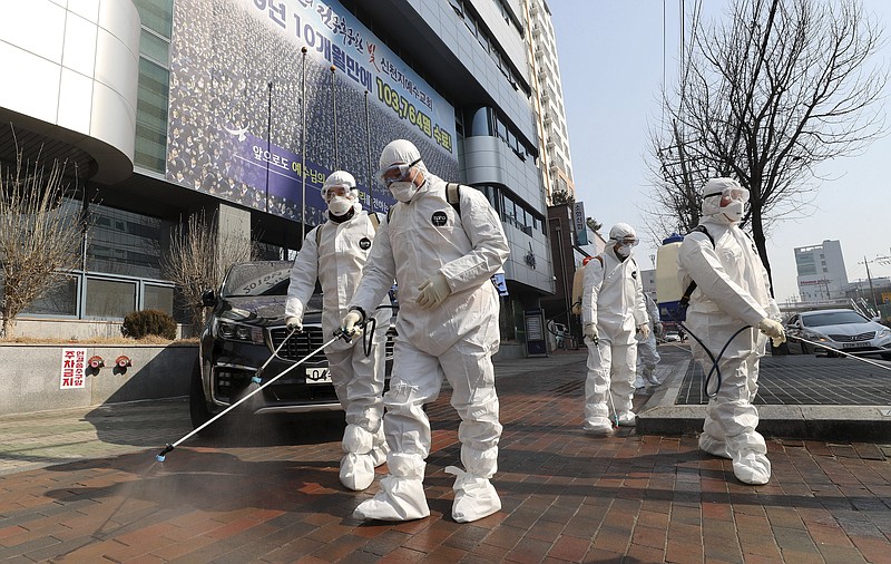 Workers wearing protective gears spray disinfectant against the new coronavirus in front of a church in Daegu, South Korea, Thursday, Feb. 20, 2020. The mayor of the South Korean city of Daegu urged its 2.5 million people on Thursday to refrain from going outside as cases of the new virus spike. (Kim Jun-beom/Yonhap via AP)