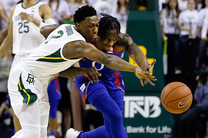Baylor guard Devonte Bandoo, left, and Kansas guard Marcus Garrett, right, reach for the loose ball during the first half of an NCAA college basketball game on Saturday, Feb. 22, 2020, in Waco, Texas. (AP Photo/Ray Carlin)