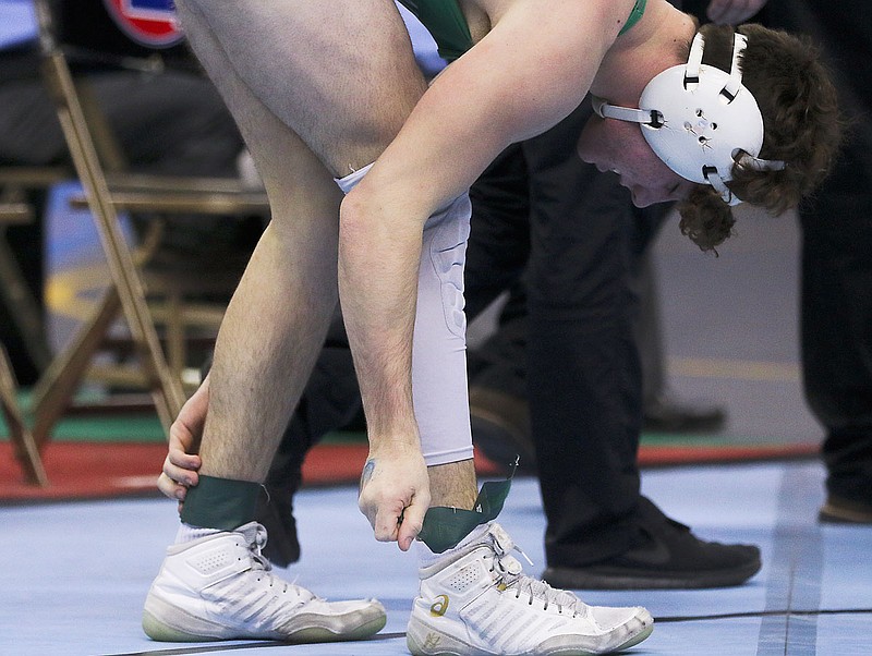 Levi Haney of Blair Oaks takes off his ankle wraps after losing by fall to Ethan Umfleet of Monett during a third-place match at 160 pounds Saturday at the state wrestling championships at Mizzou Arena.