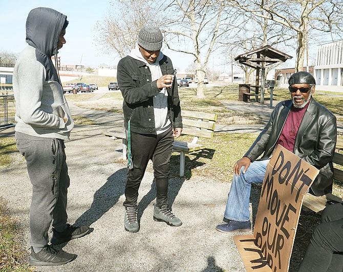 Jarret Smith, left, looks on as Daron Waters records Hans Overton as he talks to a reporter Wednesday about his opposition to the possible relocation of East Miller Park, known as the "Black Top." On Feb. 11, the Jefferson City Parks and Recreation Commission voted to give the land to the U.S. Department of Veterans Affairs if they decide to expand the Jefferson City National Cemetery across the street. 