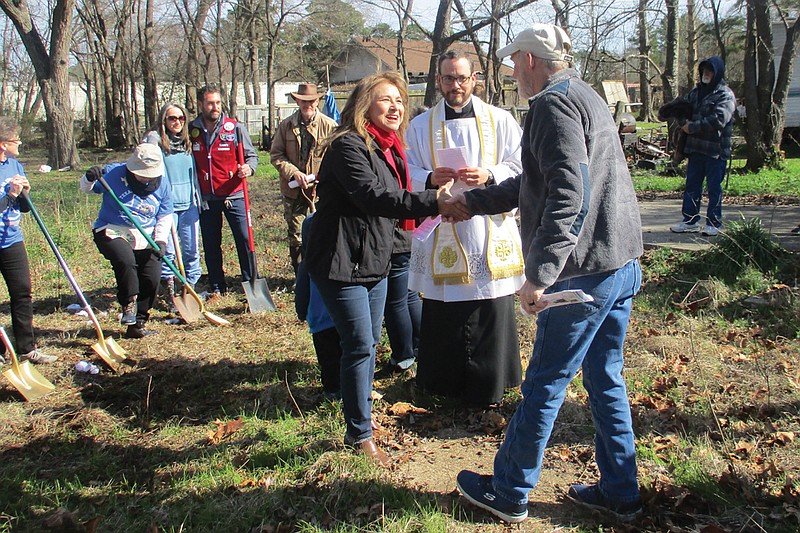 Local Habitat For Humanity Executive Director Mary Wormington, left,  shakes hands with Redwater, Texas, Mayor Pro Tem Leo Whelchl on Saturday as the Rev. Father Justin Braun of Sacred Heart Catholic Church looks on. 