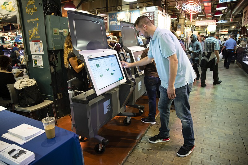 FILE - In this June 13, 2019, file photo, Steve Marcinkus, an Investigator with the Office of the City Commissioners, demonstrates the ExpressVote XL voting machine at the Reading Terminal Market in Philadelphia. Nearly 1 in 5 U.S. voters will cast ballots this year on devices that look and feel like the discredited paperless voting machines they once used, yet leave a paper record of the vote. Computer security experts are warning that these so-called ballot-marking devices pose too much of a risk. Ballot-marking machines were initially developed not as primary vote-casting tools but as “accessible” alternatives for the disabled. They print out paper records that are scanned by optical readers that tabulate the vote. They cost at least twice as much as hand-marked paper ballots, which computer scientists prefer because paper can’t be hacked. (AP Photo/Matt Rourke, File)