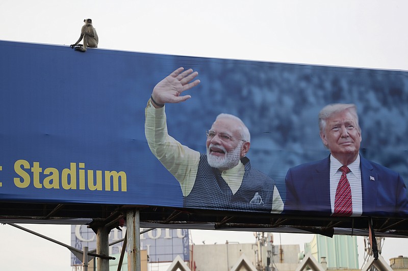 FILE- In this Feb. 19, 2020, file photo, a monkey sits on a hoarding showing India Prime Minister Narendra Modi and President Donald Trump welcoming Trump ahead of his visit to Ahmedabad, India. President Donald Trump is ready for a king's welcome as he head to India on Sunday for a jam packed two-day tour. The visit will feature a rally at one of the world's largest stadiums, a crowd of millions cheering him on and a lovefest with a like-minded leader during an election year. (AP Photo/Ajit Solanki, File)