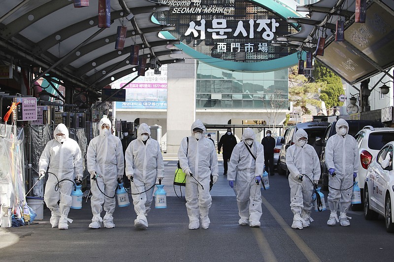 Workers wearing protective gears spray disinfectant as a precaution against the COVID-19 at a local market in Daegu, South Korea, Sunday, Feb. 23, 2020. South Korea's president has put the country on its highest alert for infectious diseases and says officials should take "unprecedented, powerful" steps to fight a viral outbreak. (Im Hwa-young/Yonhap via AP)