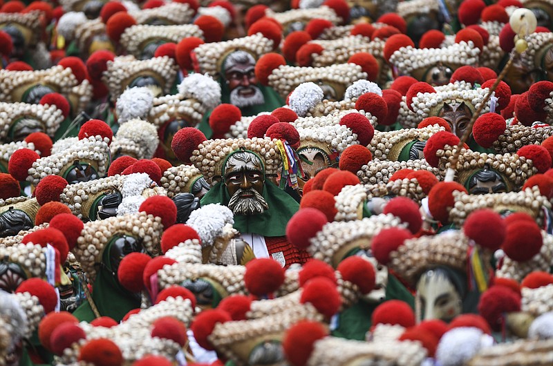 Hundreds of fools of the Elzacher Schuttig walk through the main street during the traditional Schuttig jump carnival parade in Elzach, Germany, Sunday, Feb 23, 2020. (Patrick Seeger/dpa via AP)