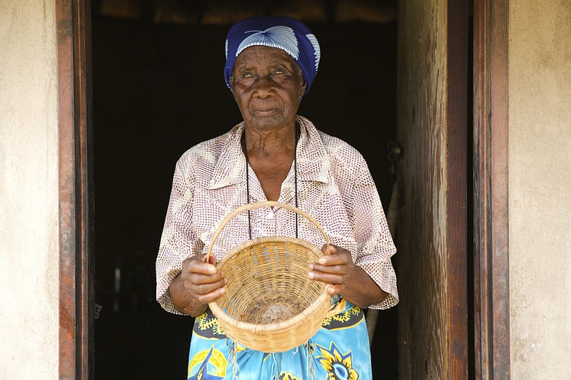 In this Thursday, Feb. 20, 2020, Leah Tsiga, stands outside her thatched hut with an empty basket in Mudzi about 230 Kilometers, northeast of the Zimbabwean capital Harare. Living alone in Zimbabwe’s arid Mudzi district, Leah Tsiga's best friend is her cat. But when it comes to food, each has to look for their own and the 90-year-old Tsiga often comes second best. The crafty feline forages in nearby bushes for rats, birds, insects and worms. As for the frail Tsiga, she sometimes goes for days without a solid meal, as Zimbabwe is ravaged by a combination of drought and deepening economic crisis. (AP Photo/Tsvangirayi Mukwazhi)