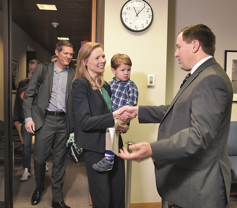 Missouri Secretary of State Jay Ashcroft, right, greets State Auditor Nicole Galloway as she proceeds to file the necessary paperwork Tuesday to officially run for governor as a Democrat. She was joined by her husband, Jon Galloway, in background, and her son, Joseph, 3, for the formalities and the news conference that followed.