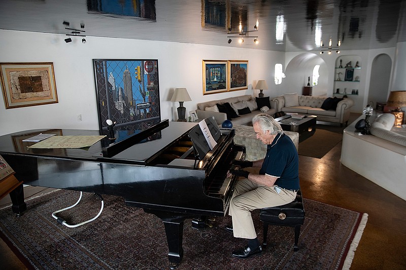 Brazilian pianist Joao Carlos Martins plays the piano wearing bionic gloves at his home in Sao Paulo, Brazil, Wednesday, Jan. 22, 2020. Martins, 79, was for decades Brazil's most acclaimed pianist, but an accident an a degenerative disease forced him to stop playing with both hands since 1998. That changed a few months ago when a new friend came to him with a pair bionic gloves that suit him perfectly. He can now play again with nine out of ten fingers. (AP Photo/Andre Penner)