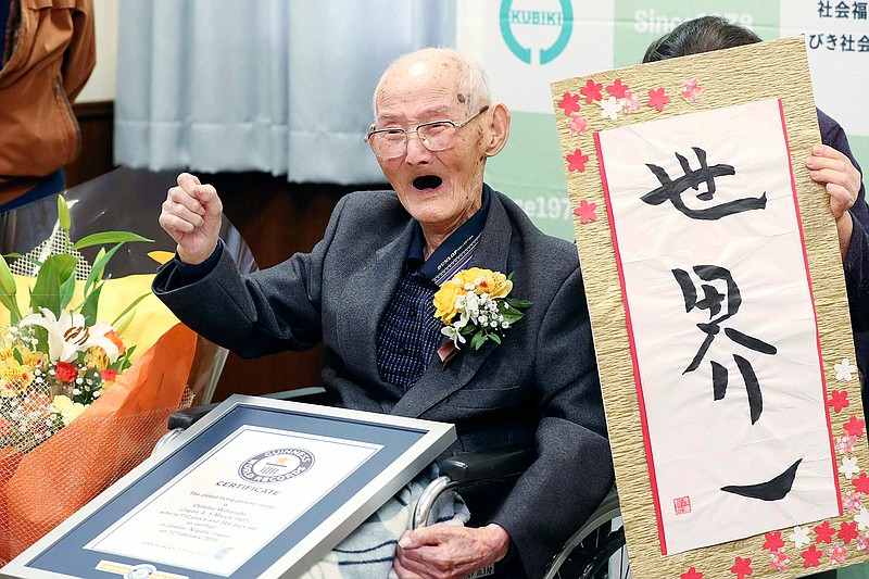 In this Feb. 12, 2020, file photo, Chitetsu Watanabe, 112, poses next to the calligraphy he wrote after being awarded as the world's oldest living male by Guinness World Records, in Joetsu, Niigata prefecture, northern Japan. The Japanese man who received his certificate as the world's oldest man with a raised fist and big smiles earlier this month has died at 112. Guinness World Records confirmed Tuesday, Feb. 25, 2020 he had died Sunday. (Kyodo News via AP, File)