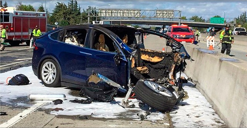 In this March 23, 2018, file photo provided by KTVU, emergency personnel work a the scene where a Tesla electric SUV crashed into a barrier on U.S. Highway 101 in Mountain View, Calif.  The National Transportation Safety Board says the driver of a Tesla SUV who died in a Silicon Valley crash two years ago was playing a video game on his smartphone at the time. Chairman Robert Sumwalt said at the start of a hearing Tuesday, Feb. 25, 2020 that partially automated driving systems like Tesla's Autopilot cannot drive themselves. Yet he says drivers continue to use them without paying attention. (KTVU-TV via AP, File)