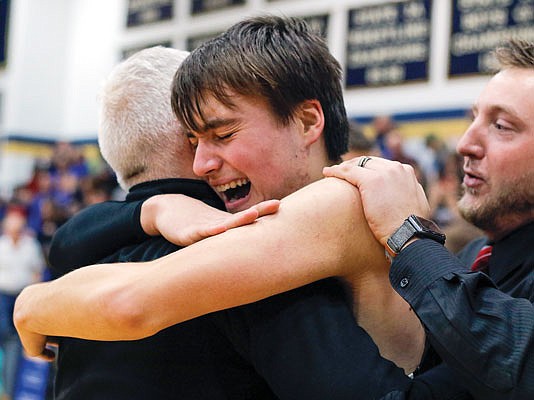 Dyson Samson embraces Eugene head coach Craig Engelbrecht as assistant coach Garrett Haslag places his hand on Samson's shoulder after Wednesday night's Class 2 sectional overtime win against New Franklin at Rackers Fieldhouse.