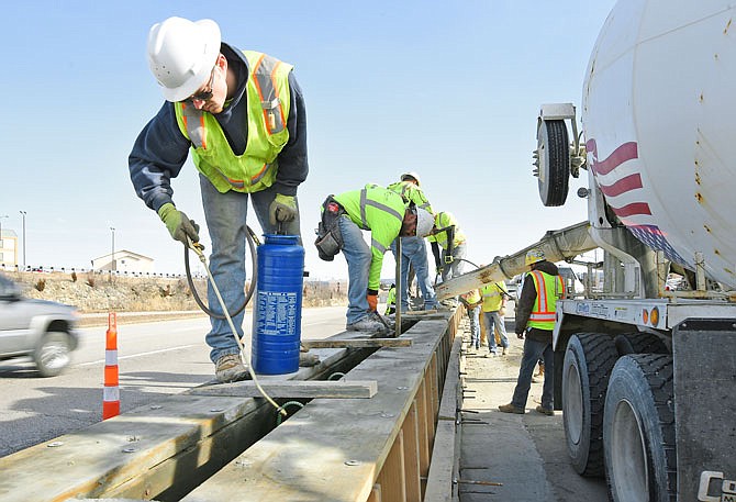 Alex Smith uses a pump sprayer to apply a release agent to the form where concrete will soon be poured. Behind him is co-worker John Lewis. They are part of a crew from GC Paving in Montreal, Missouri, working on constructing the concrete barrier between U.S. 54 and Christy Drive.
