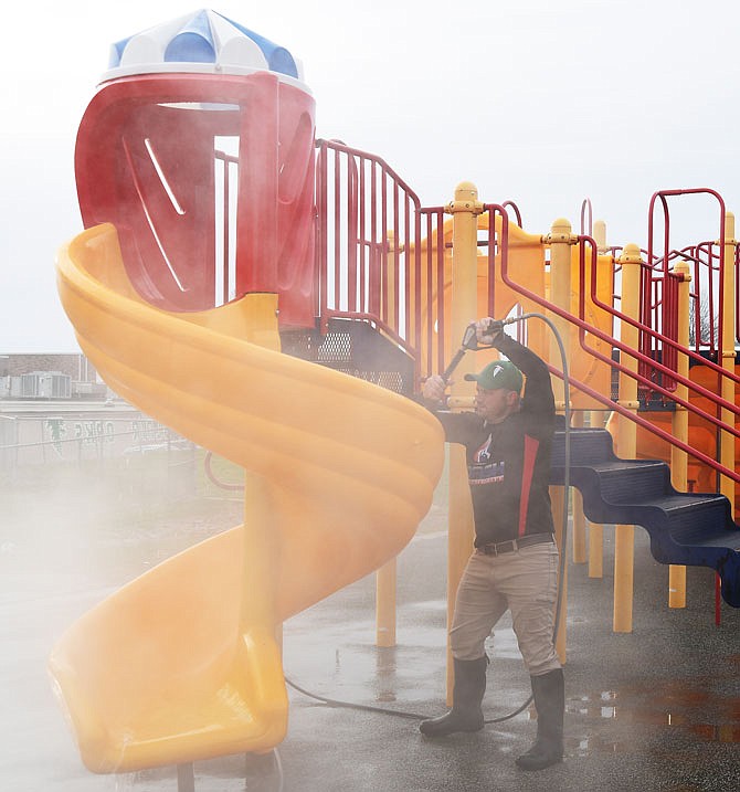 Steam surrounds Eric Wulff of Wash Authority on Friday, March 13, 2020, as he spends the early hours cleaning playground equipment at Blair Oaks Elementary School. In recognition of Random Acts of Kindness Day in February, Wulff and his wife, Karen Loaiza-Wulff, owners of the Jefferson City power washing company, decided to clean playgrounds at four schools. Due to the overwhelming response, they increased it to 10 schools.