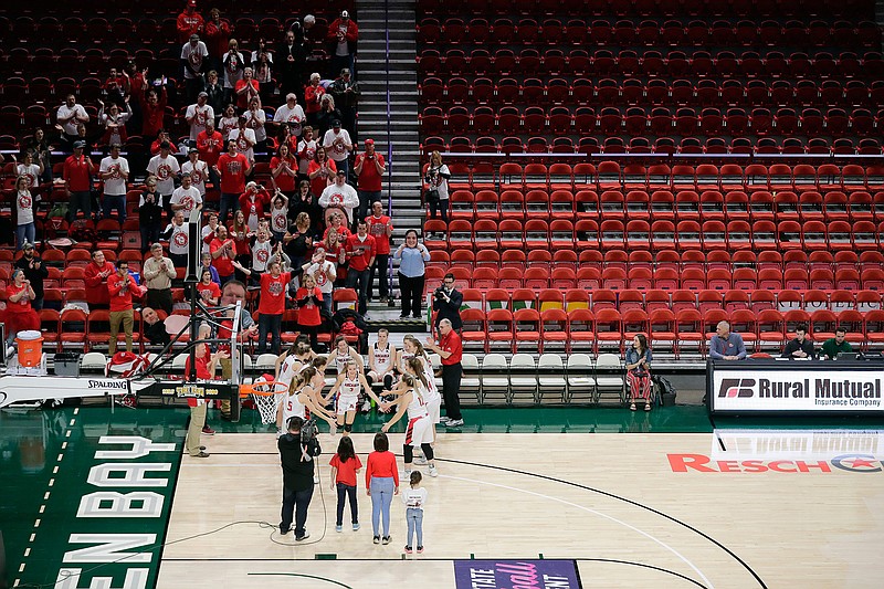 The stands are mostly empty as a small crowd cheers as Arcadia High School is announced before a Div. III semifinal game against Platteville High School at the WIAA girls state basketball tournament Thursday, March 12, 2020, at the Resch Center in Ashwaubenon, Wis. Wisconsin Gov. Tony Evers declared a public health emergency, the state Capitol closed to formal tours and the state high school athletics association moved to drastically limit attendance at remaining winter tournaments Thursday as officials scrambled to prevent the further spread of the new coronavirus in Wisconsin. (Dan Powers/The Post-Crescent via AP)