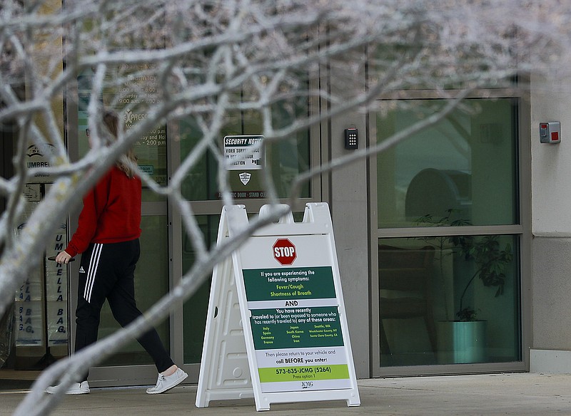 Liv Paggiarino/News Tribune

A woman walks through the doors and past a sign listing possible symptoms of coronavirus at Jefferson City Medical Group on Tuesday. Other signs cautioned limited entry through specific parts of the medical facility, such as the cancer center and the women’s and children’s center.