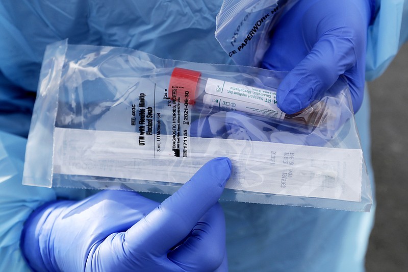 FILE - In this March 17, 2020, file photo a health worker displays the packaged nasopharyngeal swab, which goes about two inches into the nasal cavity, used on patients at a drive-through COVID-19 testing station for University of Washington Medicine patients in Seattle. A backlash roiled across social media Wednesday, March 18, as several celebrities and professional athletes revealed that they had been tested for the coronavirus, even when they didn’t have a fever or other tell-tale symptoms. (AP Photo/Elaine Thompson, File)