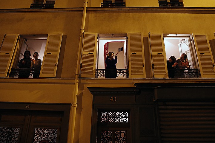 Parisians applaud the caregivers and police for their work, as the coronavirus ravaged communities across the country, in Paris, Wednesday, March 18, 2020. In France at 8pm sharp local time French citizens leaned out of windows and dangled from balconies and began applauding and whistling in unison to thank those on the front lines of the pandemic that has already claimed scores of lives. The move was an organized initiative that began circulating on social media. France has been on effective lockdown since midday on Tuesday as French President Emmanuel Macron tightened restrictions on movement to fight the spread of the virus. (AP Photo/Francois Mori)