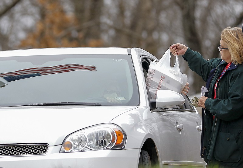 Liv Paggiarino/News TribuneDee Dee Cryderman hands boxes of food Friday to a customer as part of American Legion Post 5’s curbside chicken and fish dinner service. A pick-up and take-out option was always available for these dinners, but this is the first time the legion offered curbside delivery. 