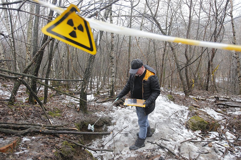 In this photo taken on Thursday, Feb. 27, 2020, Alexei Ozerov, physicist and activist fighting against turning a nuclear waste repository into a construction site of a highway, measures radiation levels at the place in southeastern Moscow, Russia. Activists in Moscow are vowing to persist with a campaign against plans to bulldoze a highway through a radioactive waste site, despite a police crackdown with mass detentions. The campaign started two months ago as a small grassroots effort to stop construction of a multi-lane motorway that is supposed to go through a plot of land where at least 60,000 tons of nuclear waste are buried. (AP Photo/Alexander Zemlianichenko Jr)