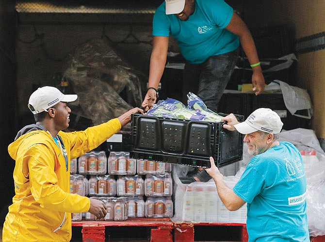 Clockwise from left, David Mazimano, Yusuf Mohammed and John Doyle unload boxes of fresh lettuce Wednesday off the Catholic Charities cargo truck onto a cart to bring into the Clarke Senior Center. The organization's next stop of the day was Eldon.