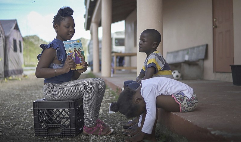 In this March 2, 2020 photo, Keline pretends to be a teacher to kids living in a tent camp based ch in Marsh, Harbour, Bahamas. The tents serve as a temporary housing solution following Hurricane Dorian ravaging the Bahamas in September. (Mackenzie Behm/Fresh Take Florida via AP)