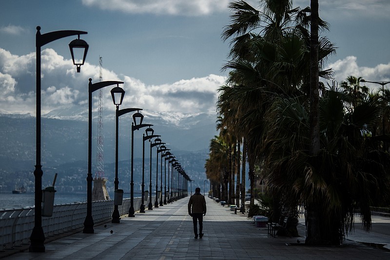 A man walks at Beirut's seaside corniche, or waterfront promenade, along the Mediterranean Sea, which is almost empty of residents and tourists in Beirut, Lebanon, Saturday, March 21, 2020. For most people, the new coronavirus causes only mild or moderate symptoms, such as fever and cough. For some, especially older adults and people with existing health problems, it can cause more severe illness, including pneumonia. (AP Photo/Hassan Ammar)