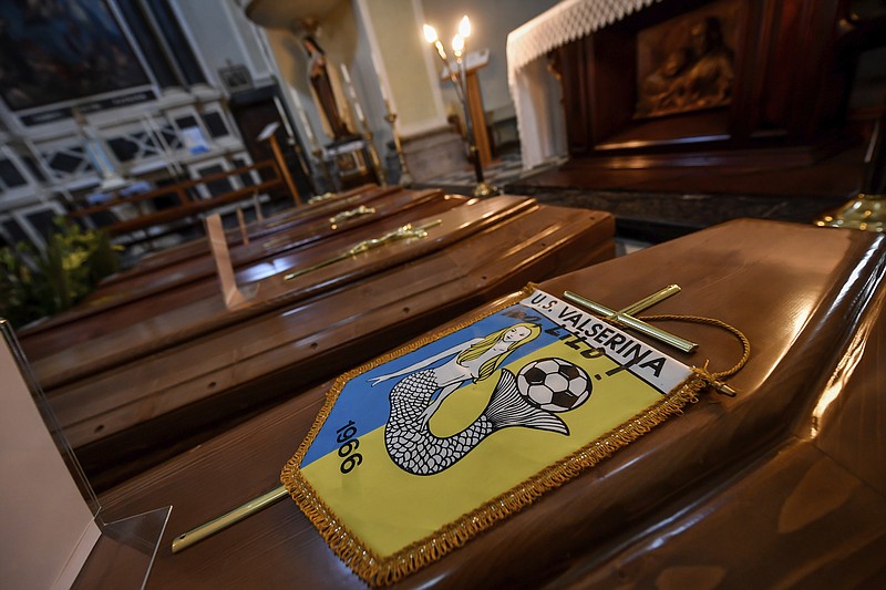 Coffins, one of them with the pennant of the local soccer team, wait to be transported to cemetery, in the church of Serina, near Bergamo, Northern Italy, Saturday, March 21, 2020. Italy’s tally of coronavirus cases and deaths keeps rising, with new day-to-day highs: 793 dead and 6,557 new cases. For most people, the new coronavirus causes only mild or moderate symptoms. For some it can cause more severe illness. (Claudio Furlan/LaPresse via AP)