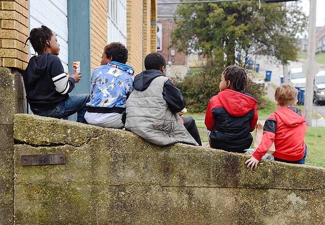 These boys sat on a concrete wall Wednesday, March 18, 2020, to enjoy their sandwich and chips after receiving a brown bag lunch at Building Community Bridges. 