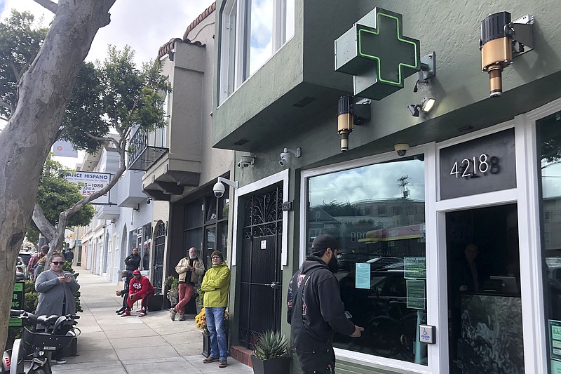 Customers maintain social distance while waiting to enter The Green Cross cannabis dispensary in San Francisco, Wednesday, March 18, 2020. As about 7 million people in the San Francisco Bay Area are under shelter-in-place orders, only allowed to leave their homes for crucial needs in an attempt to slow virus spread, marijuana stores remain open and are being considered "essential services." (AP Photo/Haven Daley)