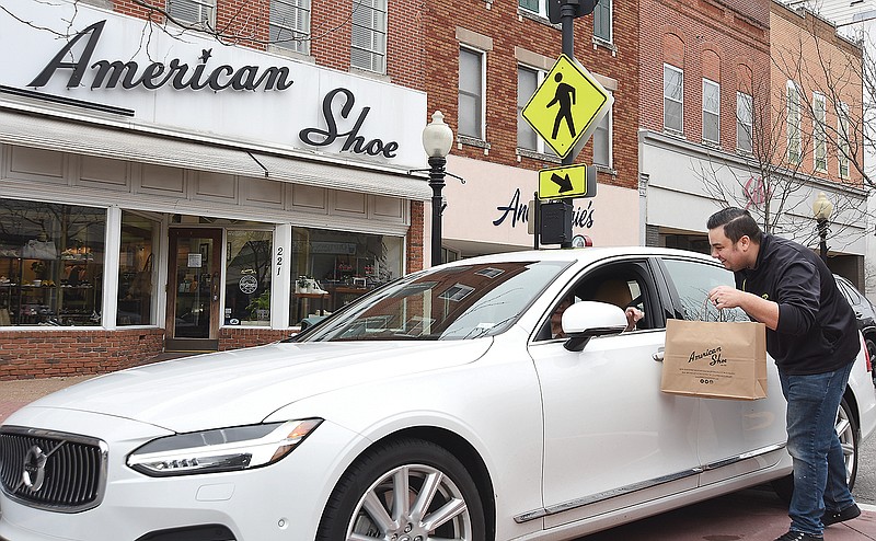 Luke Quinn, of downtown's American Shoe, delivers a purchase to a customer outside the front door. Like many restaurants and other businesses, the new normal for the time being is curbside delivery. Although the store was opened Friday and Saturday and likely lock the doors today but they emphasize they will be in the store to fill/deliver orders.