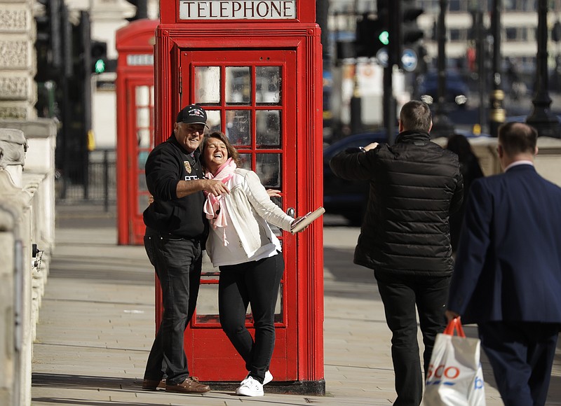 Two tourist have their photo taken next to a traditional red telephone box in Westminster, London, Monday, March 23, 2020. The British government is encouraging people to practice social distancing to help prohibit the spread of Coronavirus, further restrictions may be imposed if the public do not adhere to their advice. For most people, the new coronavirus causes only mild or moderate symptoms, such as fever and cough. For some, especially older adults and people with existing health problems, it can cause more severe illness, including pneumonia. (AP Photo/Matt Dunham)
