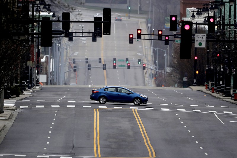 A motorist crosses an empty downtown street in Kansas City, Mo. Sunday, March 22, 2020. Officials in Missouri's largest cities are ordering a mandatory stay-at-home rule to residents starting next week in an effort to slow the spread of the coronavirus. St. Louis and St. Louis County authorities first announced the order, which is to begin Monday, before Kansas City officials followed later Saturday with a similar order. The order in Kansas City and surrounding areas is set to begin Tuesday. (AP Photo/Charlie Riedel)