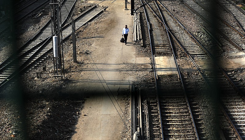 A passenger walks between railway tracks at New Delhi Railway station during a lockdown amid concerns over the spread of Coronavirus, in New Delhi, India, Monday, March 23, 2020. Authorities have gradually started to shutdown much of the country of 1.3 billion people to contain the outbreak. For most people, the new coronavirus causes only mild or moderate symptoms. For some it can cause more severe illness. (AP Photo/Manish Swarup)