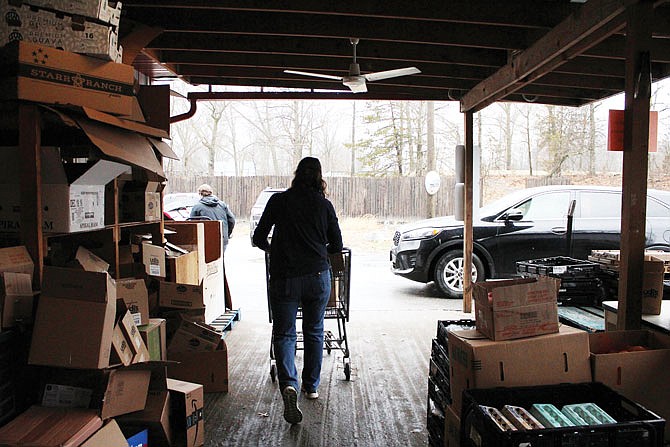 A volunteer hauls food out to a car during a recent distribution day at the SERVE food pantry. Due to high demand and low donations, the food pantry is cutting back hours — it'll now be open from 9 a.m.-3 p.m. Mondays and Thursdays.