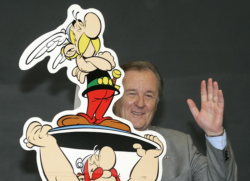 FILE - In this Oct.23, 2005 file photo, French author and illustrator Albert Uderzo waves from behind a cardboard cutout showing his comic heroes Asterix and Obelix at the 57th Frankfurt Book Fair in Frankfurt, Germany. Albert Underzo, one of the two creators of the beloved comic book character Asterix, who captured the spirit of the Gauls of yore and grew a reputation worldwide, died early Tuesday March 24, 2020. He was 92.(AP Photo/Joerg Sarbach, File)