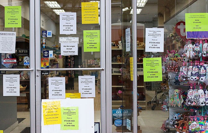 Signs with Tolson Pharmacy's contact information are plastered all over the front of the store Tuesday in downtown Jefferson City. The inside of the pharmacy is closed, but it will still fill and deliver prescriptions to your car or home.