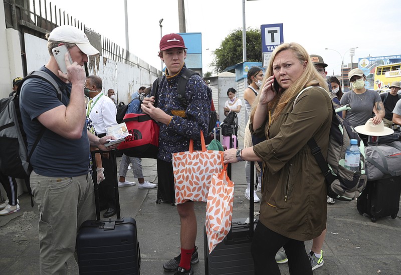 Tourists from the United States wait outside the closed Jorge Chavez International Airport for a member of the U.S. Embassy to escort them to a flight that will fly them back to the U.S., in Callao Peru, Friday, March 20, 2020, on the fifth day of a state of emergency decreed by the government to prevent the spread of the new coronavirus.  (AP Photo/Martin Mejia)