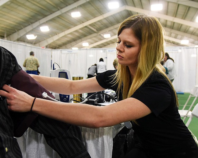 In this Feb. 24, 2018 file photo, health screener Nicole Lamb takes the blood pressure of a man as part of a wellness exposition at the Jefferson City Area YMCA. In response to the current coronavirus pandemic, the American Heart Association advises that, although people with heart disease or other underlying conditions such as hypertension aren't at higher risk of contracting COVID-19, if they do get it, the chances of complications increase greatly.