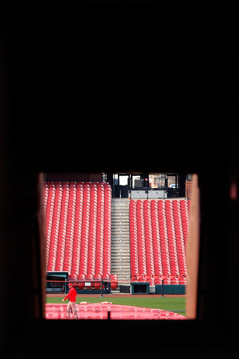 A grounds crew member walks on the field Wednesday inside Busch Stadium, home of the St. Louis Cardinals. The start of the regular season, which was set to start Thursday, is on hold indefinitely because of the coronavirus pandemic. 