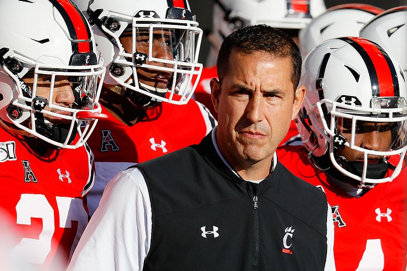 In this Saturday, Nov. 9, 2019, file photo, Cincinnati head coach Luke Fickell takes the field with his players before the first half of an NCAA college football game against Connecticut, in Cincinnati. Normally, in March, college football teams would be preparing for the upcoming season. Because of the new coronavirus pandemic, coaches are trying to figure out how to recreate some of what has been lost. Fickell said his goal is to try give his players a routine, including workout regimens they can do on their own without access to local gyms. They will also have online meetings with position groups and assistant coaches. (AP Photo/John Minchillo, File)