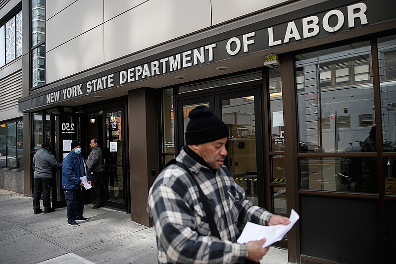 In this March 18, 2020 file photo, visitors to the Department of Labor are turned away at the door by personnel due to closures over coronavirus concerns in New York. A record-high number of people applied for unemployment benefits last week as layoffs engulfed the United States in the face of a near-total economic shutdown caused by the coronavirus. The surge in weekly applications for benefits far exceeded the previous record set in 1982.  (AP Photo/John Minchillo, File)