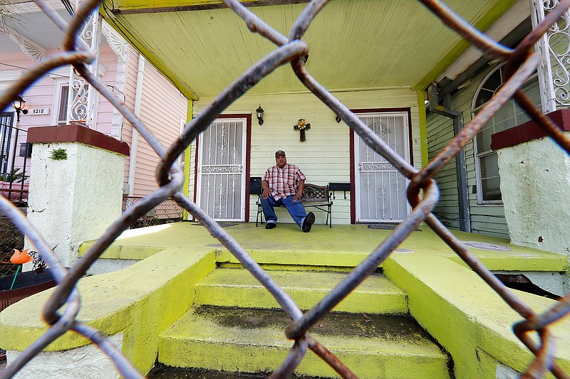 In this March 24, 2020, photo, David McGraw poses for a portrait as he sits on his front porch in New Orleans. Barely a week ago, McGraw was cooking daily for hundreds of fine diners at one of New Orleans' illustrious restaurants. Today, he's cooking for himself, at home, laid off along with hundreds of thousands of people across the U.S. in a massive economic upheaval spurred by efforts to slow the spread of the coronavirus. (AP Photo/Gerald Herbert)