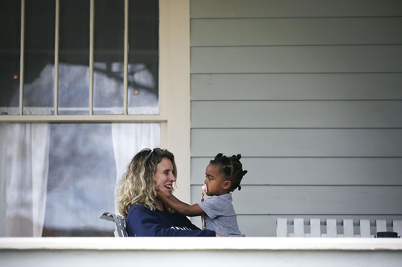 DeAnna Cooper sits on the porch with her daughter Ryan Brent,2, in Brady Heights Thursday, March 19, 2020. The family was practicing social distancing due to the coronavirus outbreak. (Mike Simons/Tulsa World/Tulsa World via AP)