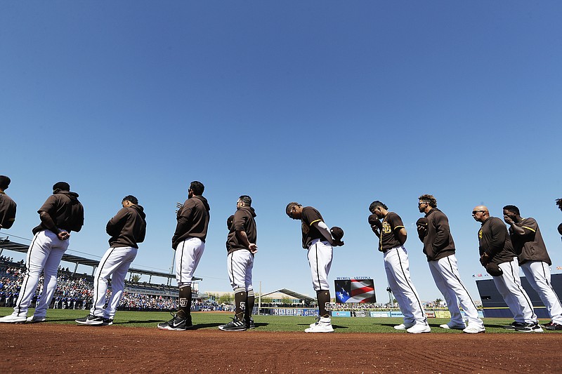 Padres players and coaches line up during playing of the national anthem before a spring training game against the Dodgers earlier this month in Peoria, Ariz.