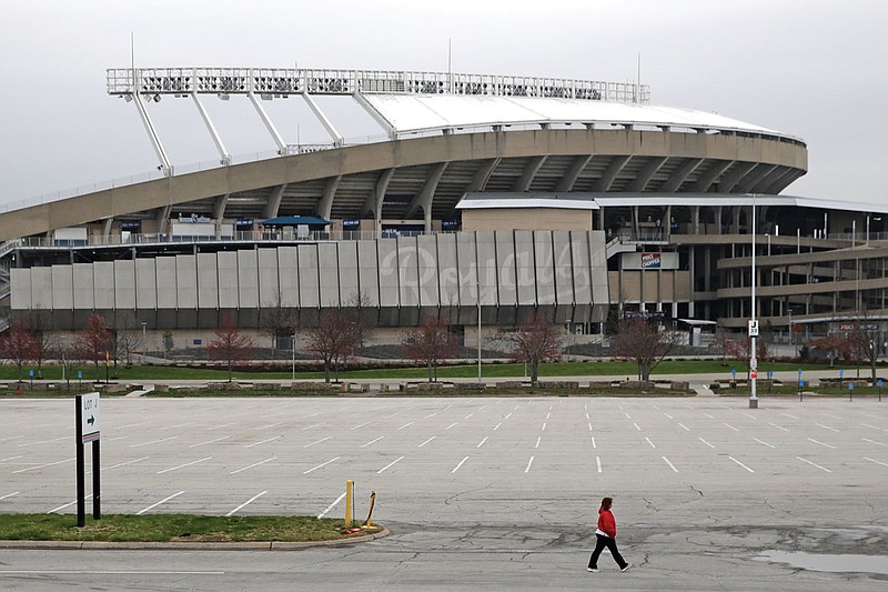 A woman walks past Kauffman Stadium, home of the Royals, on Wednesday in Kansas City. The start of the regular season, which was set to begin Thursday, is on hold indefinitely because of the coronavirus pandemic.